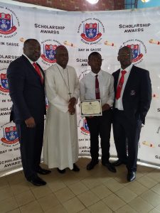 One of the laureates receiving his award from Bishop Bushu as President Itoe and Chairman Fote look on.